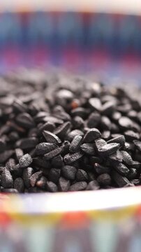 Close up of nigella sativa or black cumin seeds in a bowl with colorful patterned edges, showcasing the small, dark seeds used as a spice and for herbal remedies, static footage