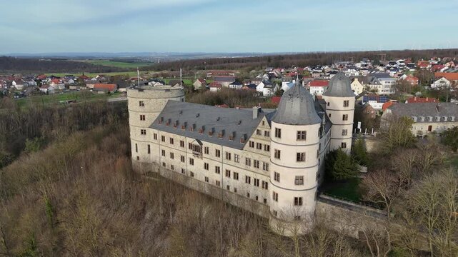 Drone shows the castle within the village landscape from a side perspective during a gentle orbital move.