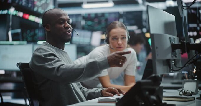 Two Professional Brokers Analyzing Big Data Trends on Multi Monitor Dashboard. Man Gestures Towards Specific Chart on Monitors While Woman Provides Input. Strategic Planning in Modern Fintech Office.