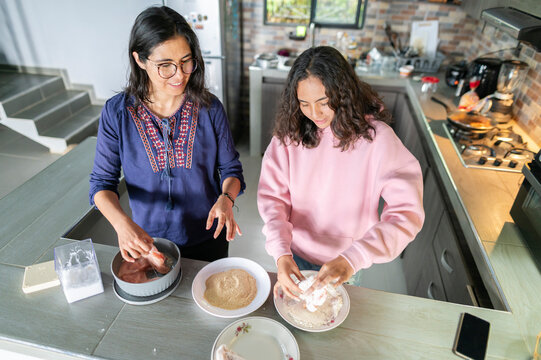 Mother and teenager bonding in home kitchen preparing food