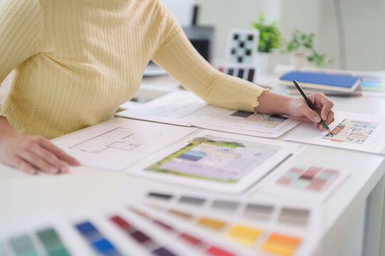 Asian adult woman architect designing drawing floor plans coloring interior designs professional creative workspace project planning color palette