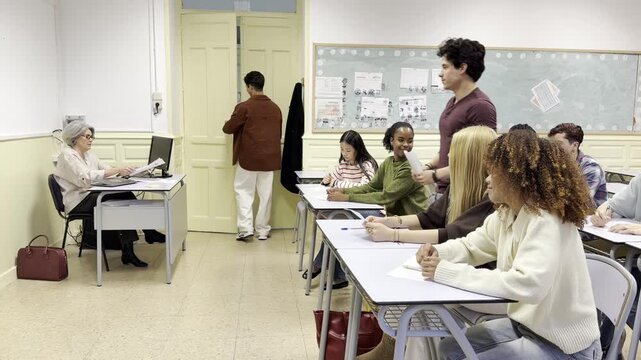 Diverse group of college students delivering their completed exams to the professor at her desk
