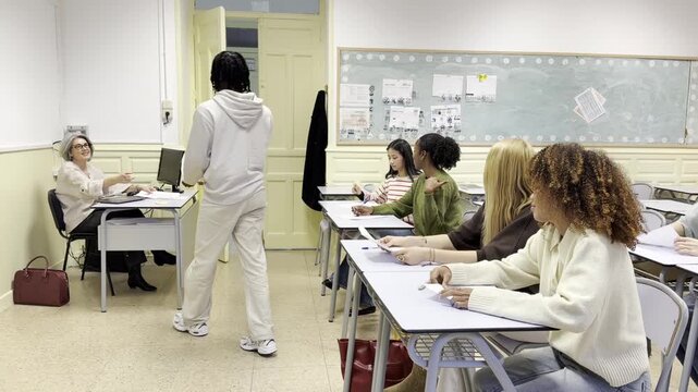 Multiethnic group of high school students delivering their completed test papers to the teacher