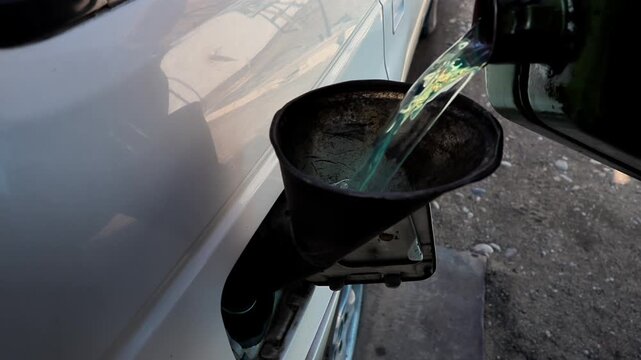Filling diesel fuel into a car through the neck using an old metal canister