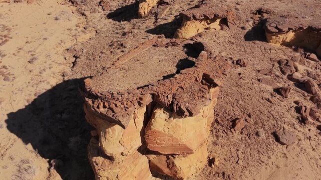 Drone aerial reveal shows the weathered stone face and architecture of an abandoned alien outpost and ancient fortress built on a barren sandstone mesa in a desolate desert world.