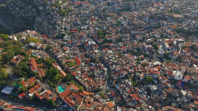Bird's-eye view of the mountains and hillsides of the town of Taxco on a sunny day, with colonial architecture of white houses and tiled roofs, Guerrero, Mexico