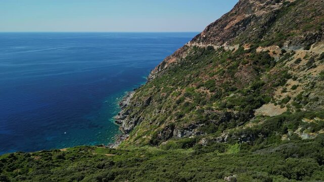 Drone aerial view of the rugged coastline in the Cap Corse region of Corsica, France. Mediterranean cliffs descending into deep blue sea with turquoise water along the wild northern coast of the islan