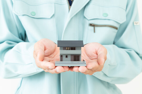 作業着を着た男性と家模型