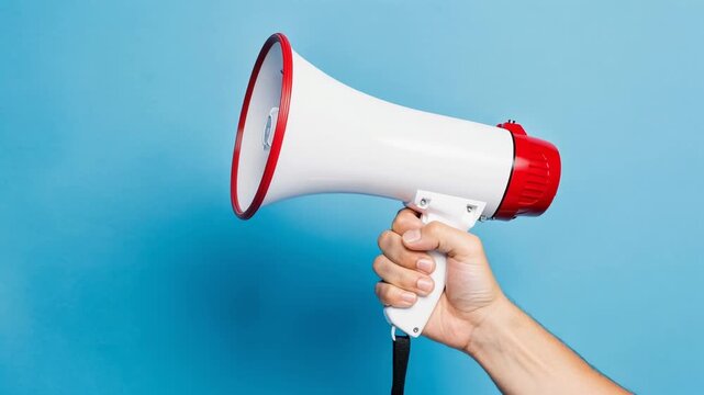 Hand holding white and red megaphone against bright blue background for communication and announcement