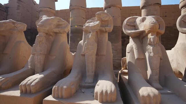 Karnak Temple in Luxor, Egypt. Close-up of ancient ram sphinx statues with pharaoh figures at Karnak Temple entrance, Luxor Egypt. 