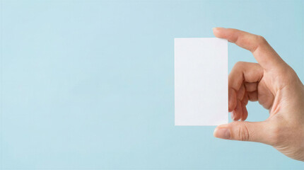 Obraz premium Blank business card mockup pinched between thumb and index finger on cold blue background 