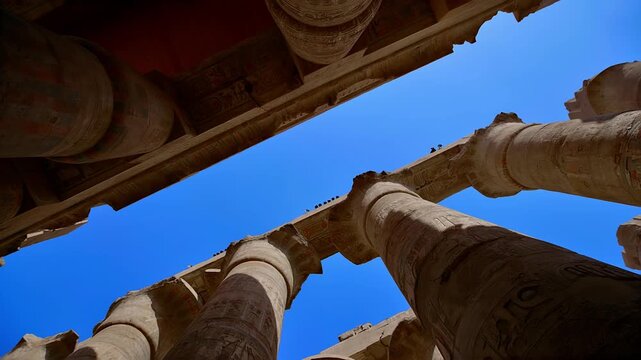 Karnak Temple in Luxor, Egypt. Great Hypostyle Hall at Karnak Temple, Luxor Egypt. Massive painted columns with original red hieroglyphics soaring against bright blue sky. 