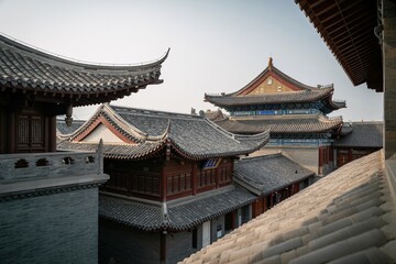 Fototapeta premium Traditional chinese architecture with tiled roofs and ornate pagoda style buildings in asian city ancient eastern buildings with gray and brown tiled roofs and decorative eaves