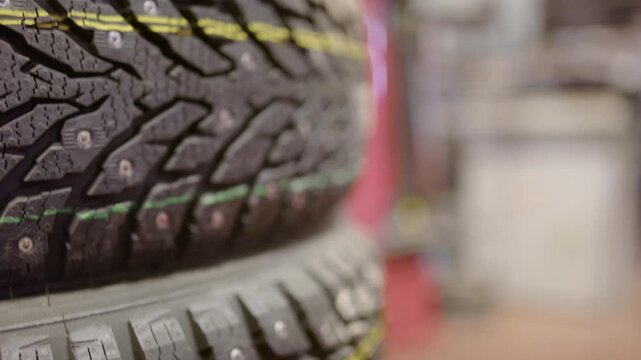 Close up view of brand new studded winter tire for car showing tread pattern and metal studs