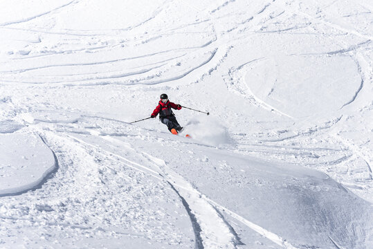 Skier in red jacket carving on a sunny day