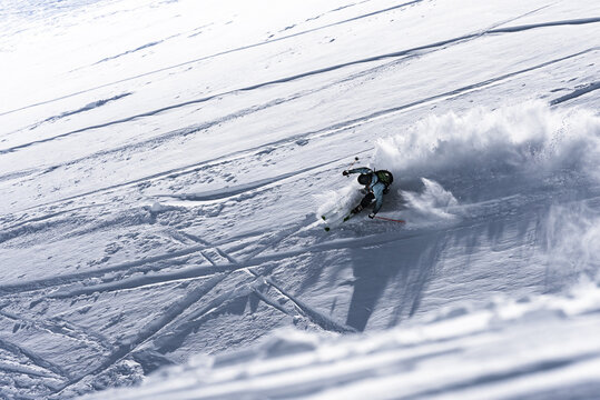 Skier making a fast turn down a powder slope