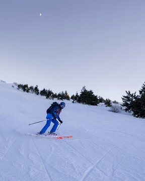 Skier on a slope at sunset with orange skis