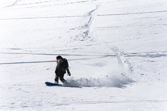 Snowboarder riding through fresh powder snow