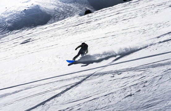 Snowboarder riding through fresh powder snow