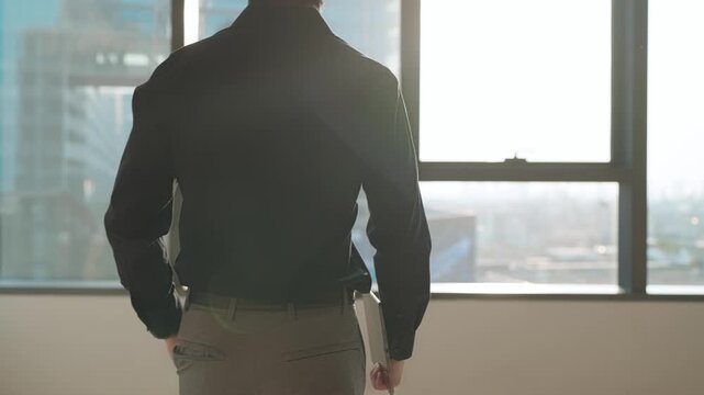 Business Vision: A man stands confidently, gazing out a window, embodying the spirit of innovation and progress in a modern urban landscape.