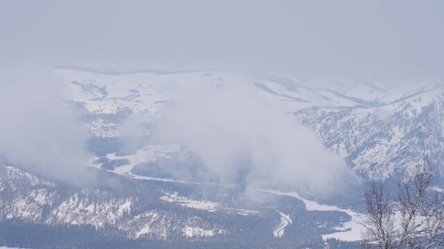 Winter Mountain Landscape. Snowcovered Peaks And Foggy Valleys. Frozen Summits Amidst Misty Mountain Valleys And Icy Air. Snowy Mountain Ranges With Peaks Cloaked In Fog And Cold Light