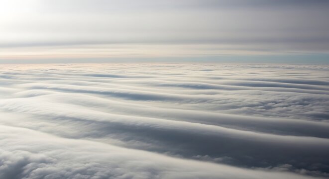 The aerial view captures rolling clouds floating above a serene landscape at sunrise.