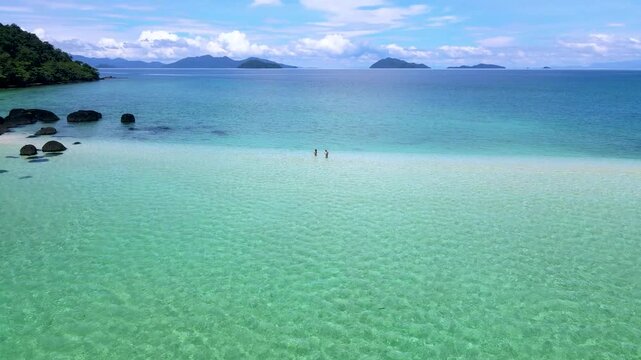 Visitors stroll through the stunning shallow waters of Koh Kham Thailand, surrounded by vibrant blue seas and serene islands. This tropical paradise is perfect for relaxation and adventure.
