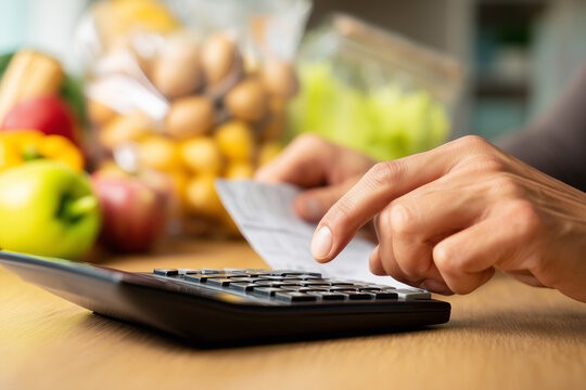 person calculating groceries cost with calculator and receipt, inflation stress