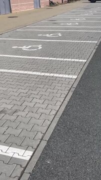 Accessibility, inclusion, and equal access in a public. Empty wheelchair parking spaces on interlocking pavers near curb with white markings and textured gray surface, parking lines and reserved lots