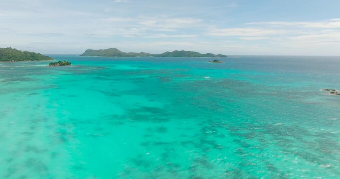 Bright turquoise waters extending towards the horizon with small islets visible. Seychelles, Praslin.