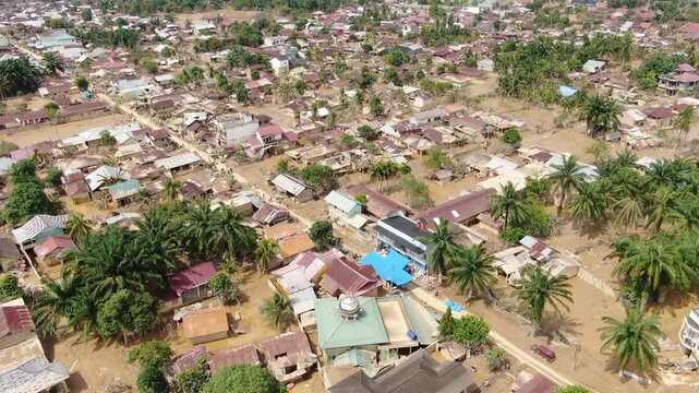 Cinematic drone orbit showing blue relief tents among damaged houses in Aceh Tamiang Indonesia filmed December 2025 capturing aftermath of November 2025 flash flood disaster