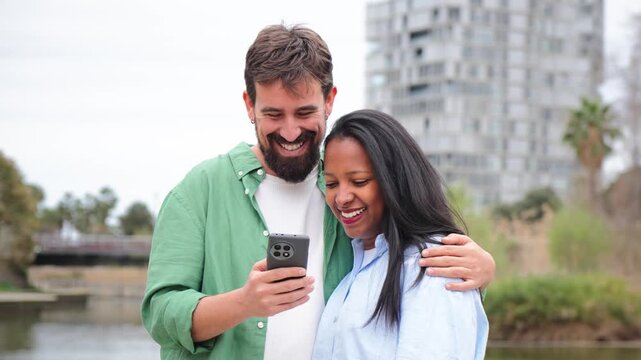 Happy couple enjoying a special moment together as they engage with a mobile phone, sharing laughter and smiles while exploring content on the device, creating a joyful and intimate experience