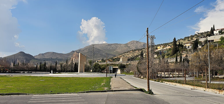 City view toward Sierra Elvira with an open paved area, monument structure and surrounding roads in Atarfe, Andalusia, Spain, documenting the town edge and nearby hills.