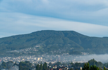 Naklejka premium Beautiful bluish and cloudy morning view of a mountain range and villages in Lembang, Bandung, West Java, Indonesia. Located near the Tangkuban Perahu volcanic mountain and the Lembang fault zone.
