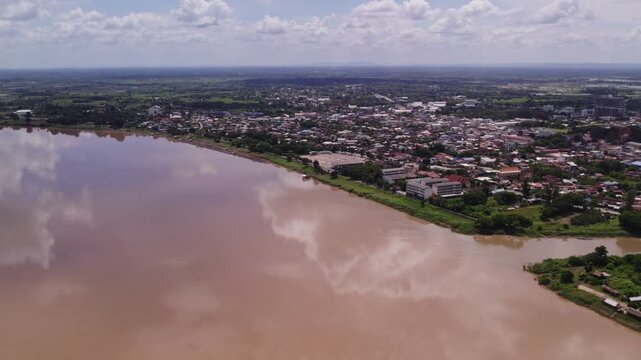 Very high flying slow forward moving view of the Mekong River during dry season with a small Thai village along the coastline.
