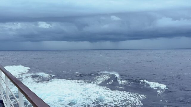 Panning from left to right from mid-ship on a cruise-liner in the Indian Ocean looking out to the storm front on the horizon and the oncoming rain storm