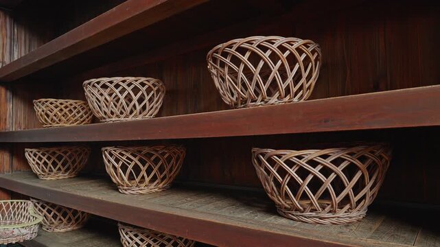 Rows of traditional hand-woven baskets for clothes arranged on wooden shelves inside a retro Japanese public bathhouse dressing area.