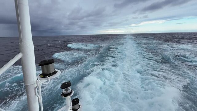 POV of aft of ship cruising through the Indian Ocean off the South African coast panning from right to left with rain storm in the distance