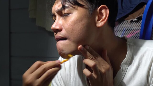 Close up of a young Asian man carefully shaving his beard and mustache with a yellow disposable razor. The video highlights daily grooming routine, male skincare, morning hygiene, and personal care fo