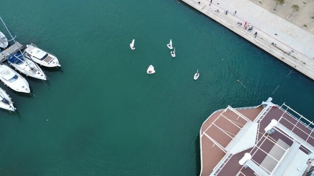Aerial top view sailing training boats in turquoise marina water