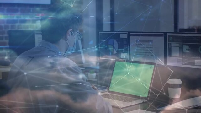 IT pro leaning forward, typing laptop with green screen and monitoring charts, cloud nodes drifting