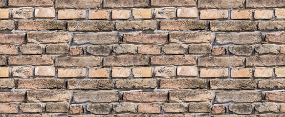 Fototapeta premium Rustic, aged brick wall texture. A seamless background featuring weathered brown and red bricks with dark mortar