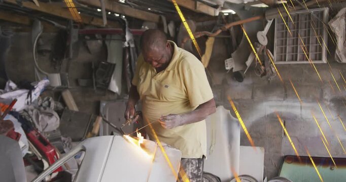 Igniting torch, man in yellow polo cutting white panel in garage, repairing with filler rod, sparks