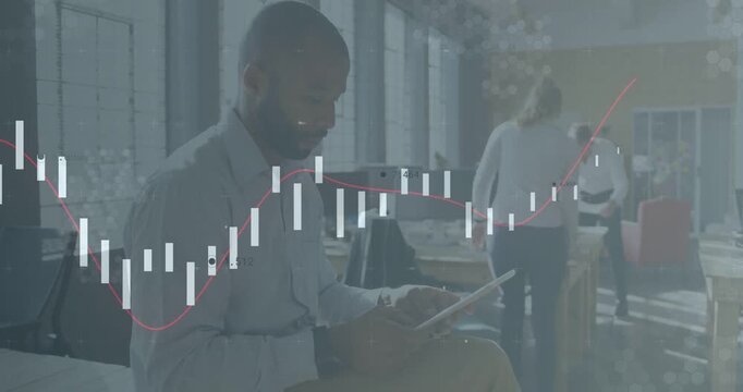 Seated analyst tapping tablet generating chart while staff adjusting laptop reviewing business data
