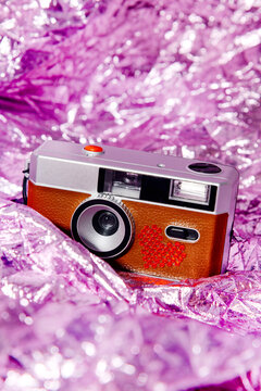 Retro film camera with rhinestone heart on violet metallic background