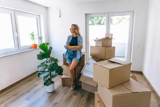 Woman unpacking cardboard boxes in new apartment indoors