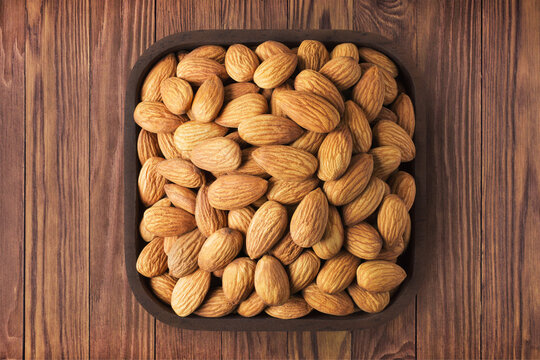 almond nuts peeled raw in square plate on wooden table background. vegetarian organic food for healthy diet.