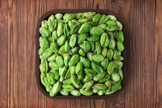 pistachios nuts peeled green in square plate on wooden table background. vegetarian organic food for healthy diet.