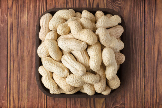 shelled peanut in square plate on wooden table background. vegetarian organic food for healthy diet.