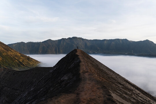 Woman hiking along volcano ridge in Java Indonesia at sunrise